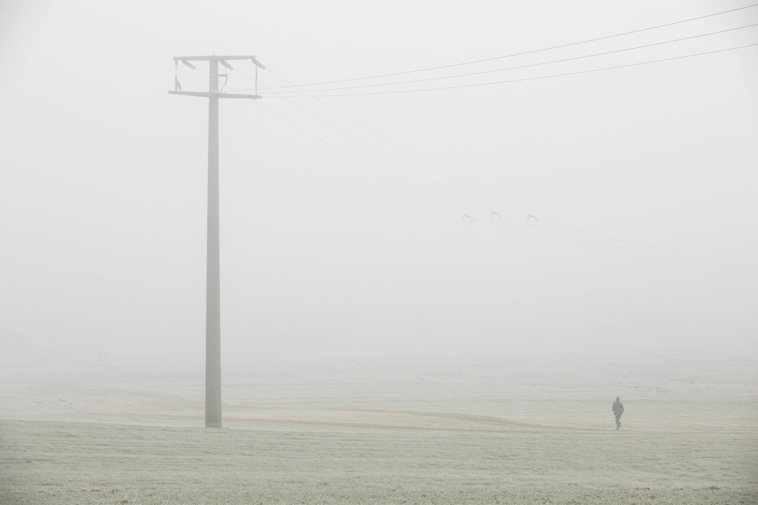 Strommasten mit Mensch im Nebel